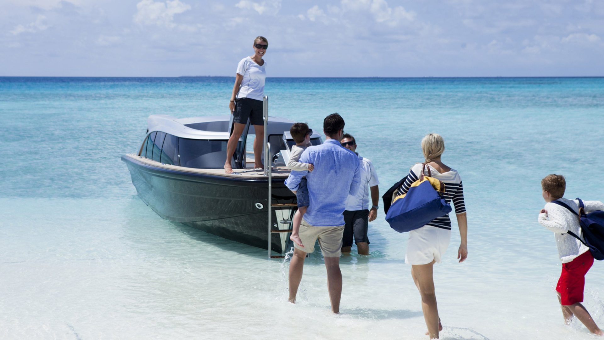 Family entering speedboat at tropical beach shoreline
